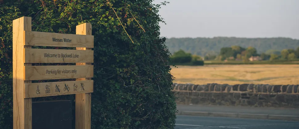 Wooden Backwell Lake Entry Sign with a view of fields behind