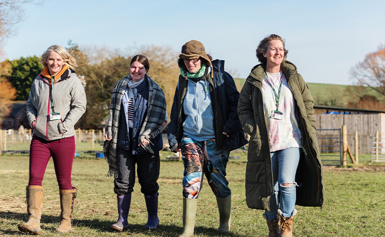 Able Hands Together Charity Workers walking in a field smiling with volunteers