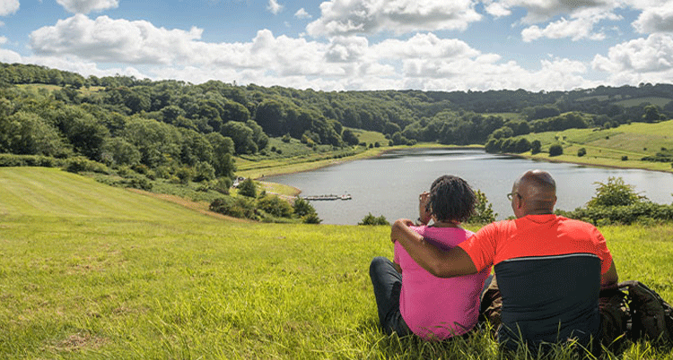 Couple sat in field overlooking Clatworthy Reservoir