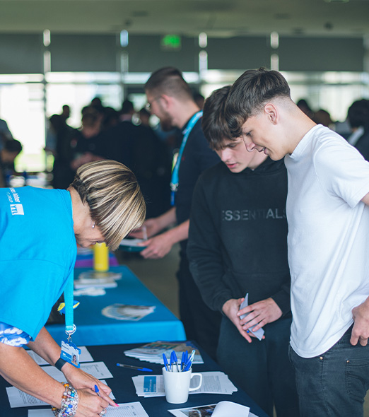 Two young male students talking to a Wessex Water employee