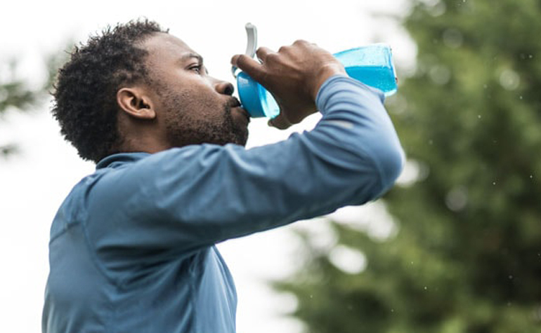 Male runner drinking water from a refillable water bottle