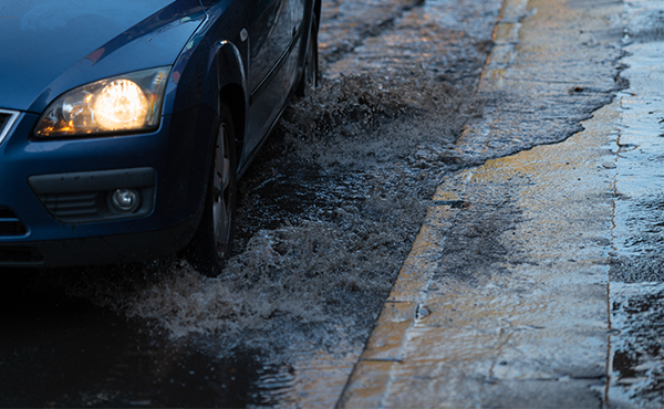 Flooding caused my excessive rain water in the road with a car driving through