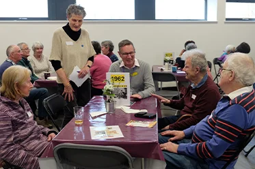 Group of elderly people sat around a table talking