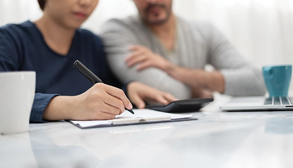 A concerned couple looking over some papers. They are using a calculator