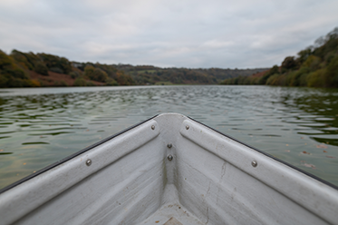 Front of boat on a reservoir with trees in the background