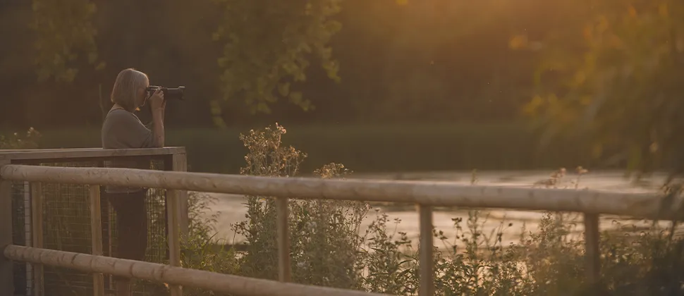 Woman taking photos of Backwell Lake during dawn